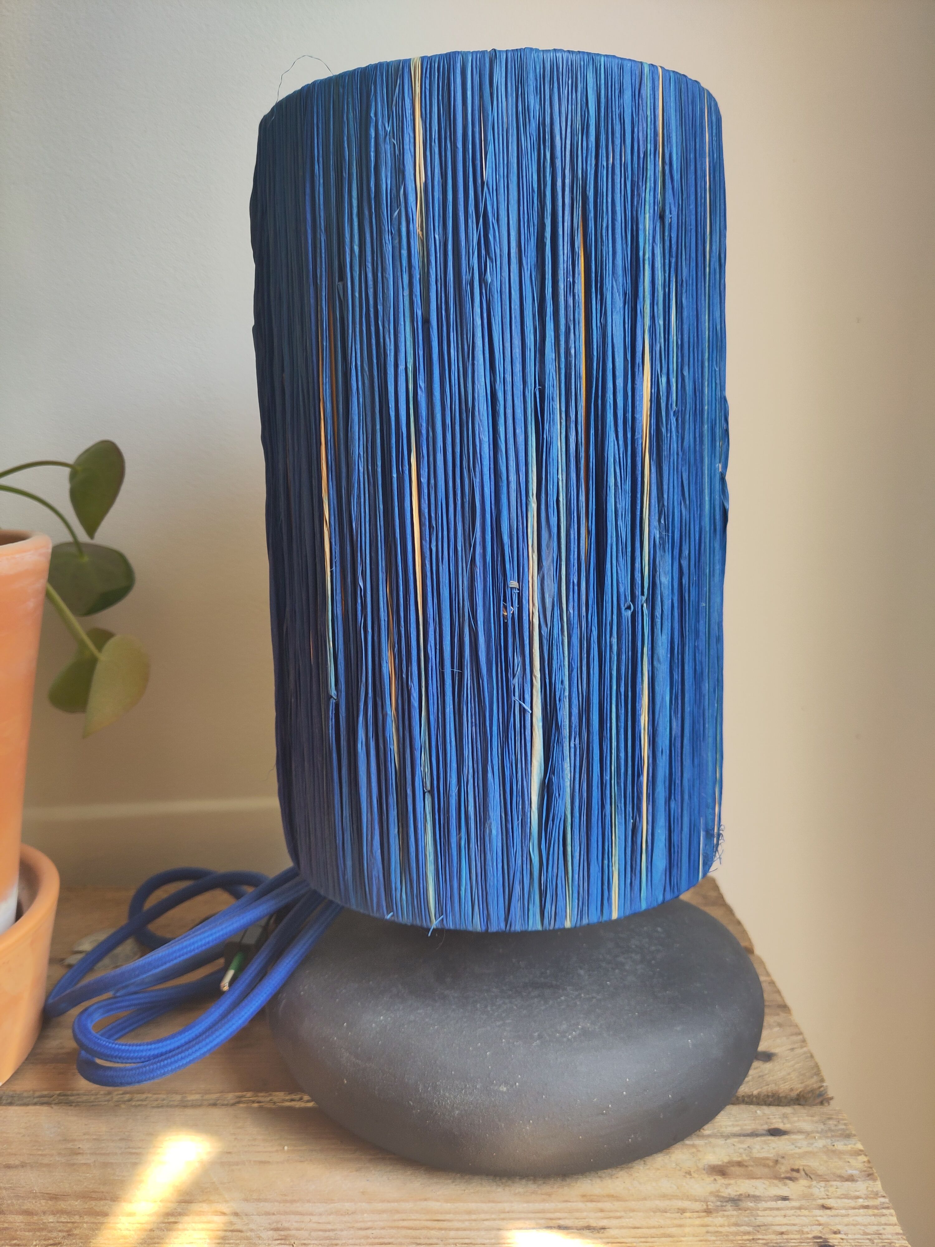 Table lamp in black stoneware and natural raffia.