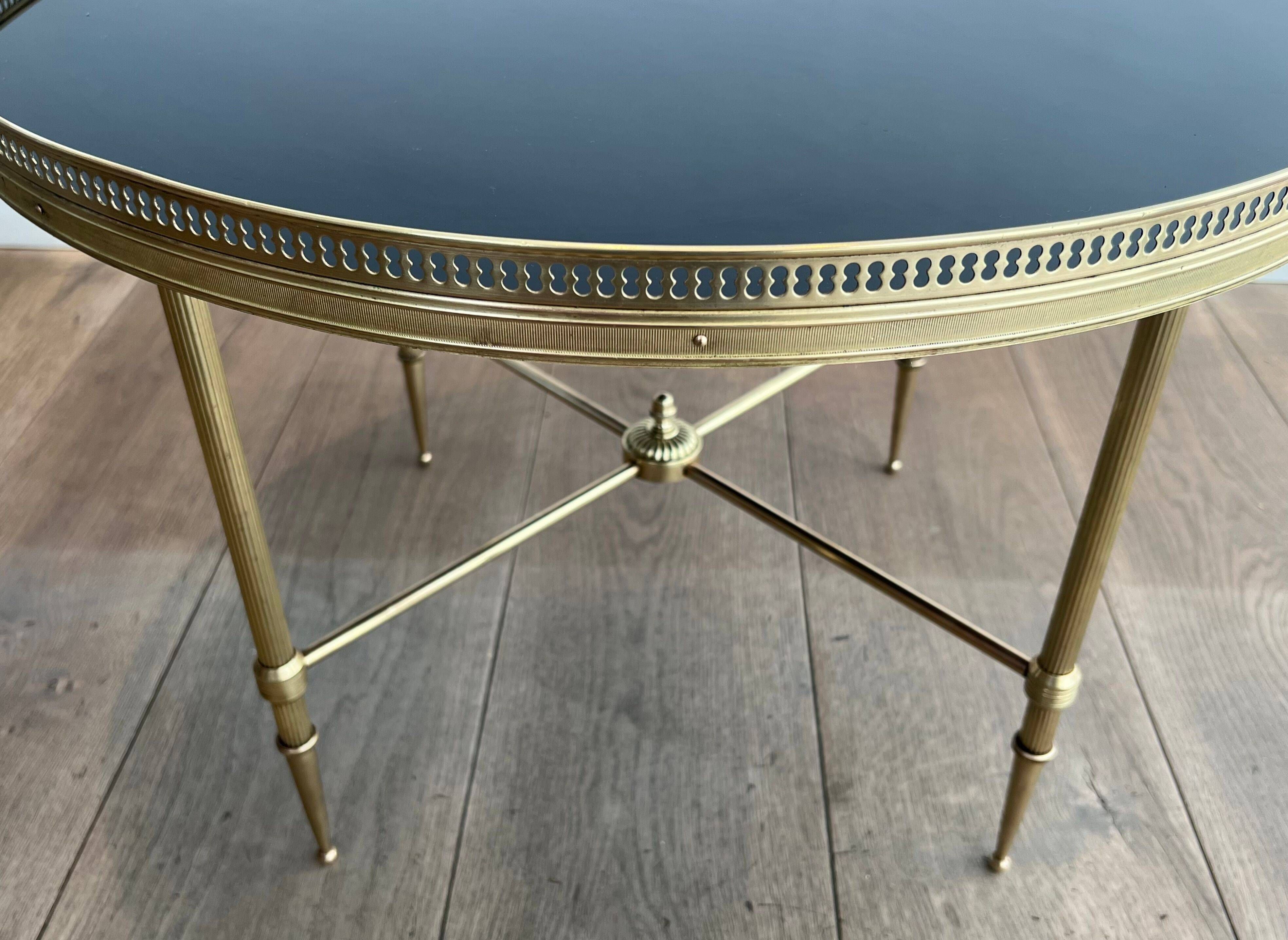 Round coffee table in brass with a black lacquered glass top from Maison Jansen.