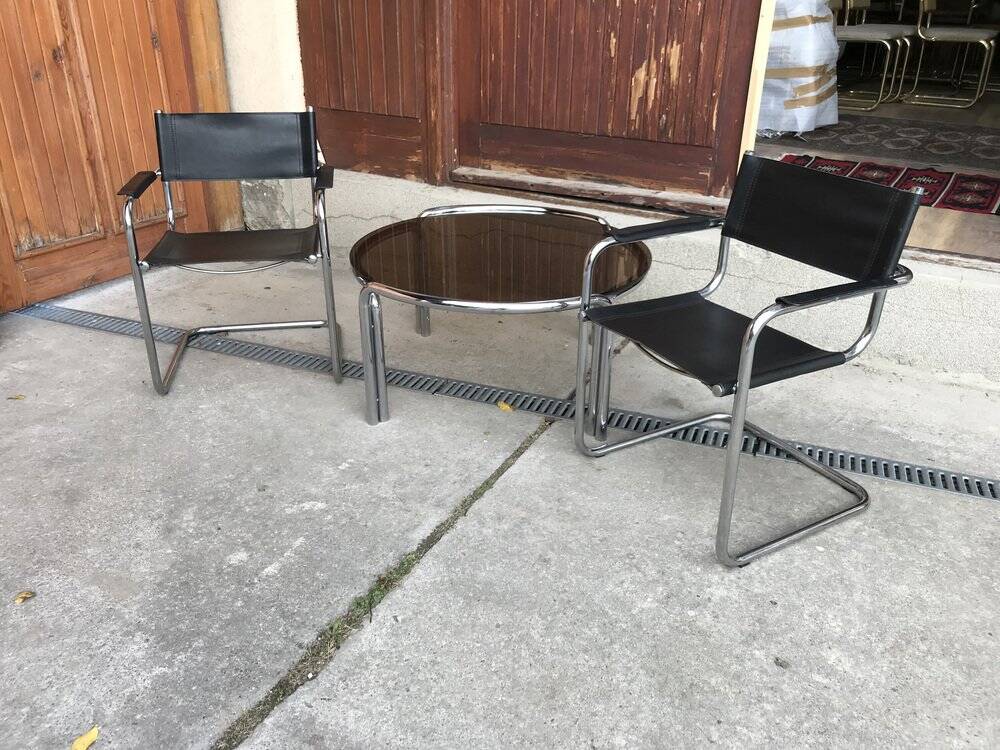 Mid-century round coffee table in chrome and smoked glass with 2 black leather chairs.