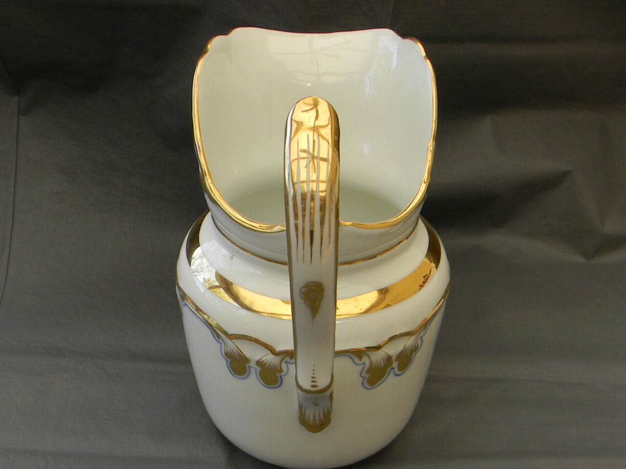 Milk jug or antique pitcher in white and gold porcelain.