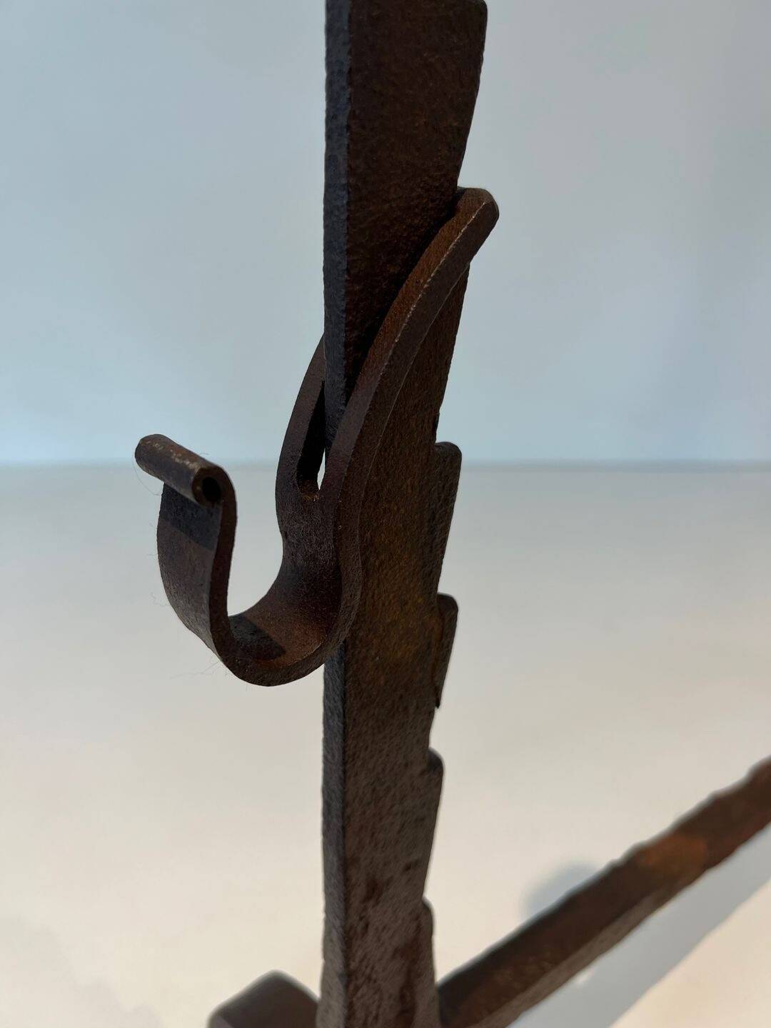 Pair of wrought iron andirons with adjustable supports and tripod feet.