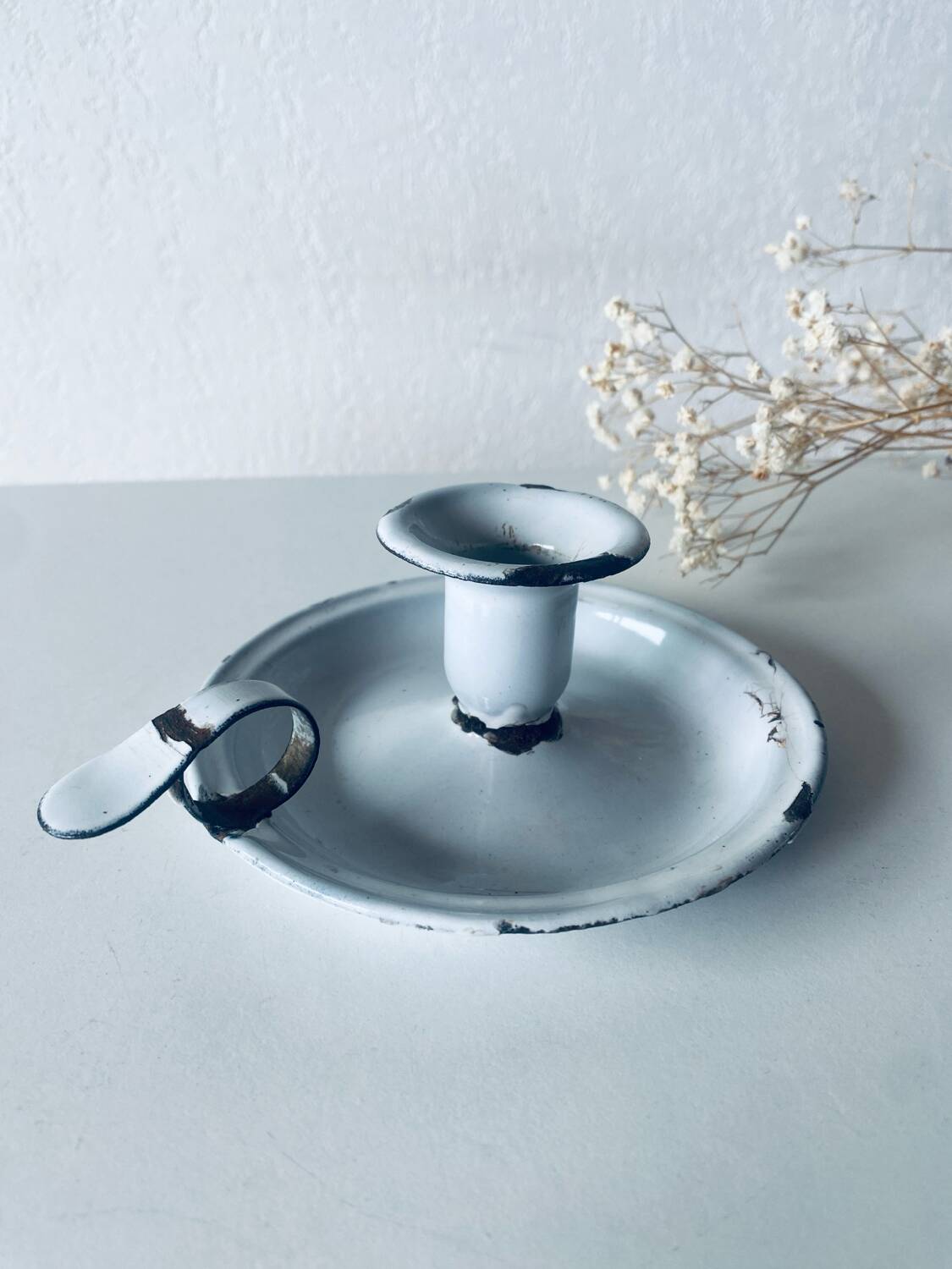 Old candle holder in white enameled metal