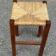 Low stool in brutalist style made of solid wood with straw, 1980.