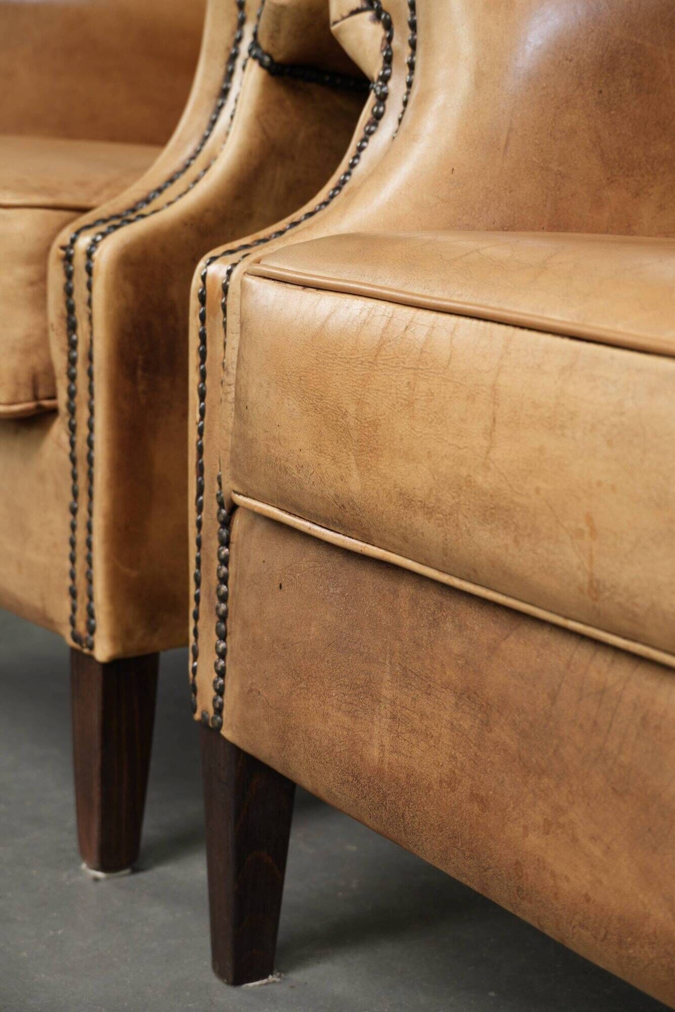 Set of two light cowhide wingback armchairs with a timeless English look