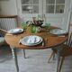 Walnut table with raised flaps, base on verdigris casters.