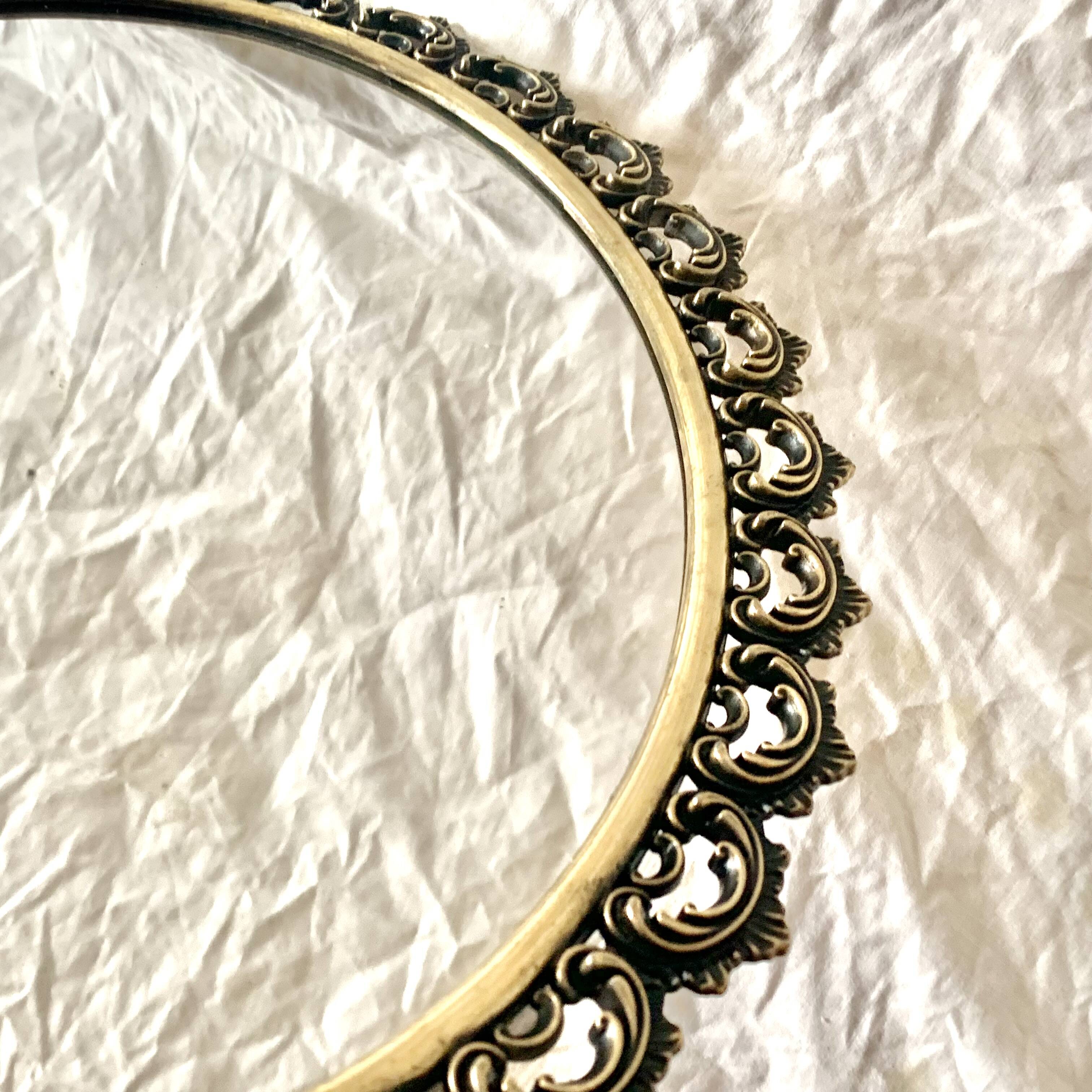 Old oval wall mirror in gilded brass