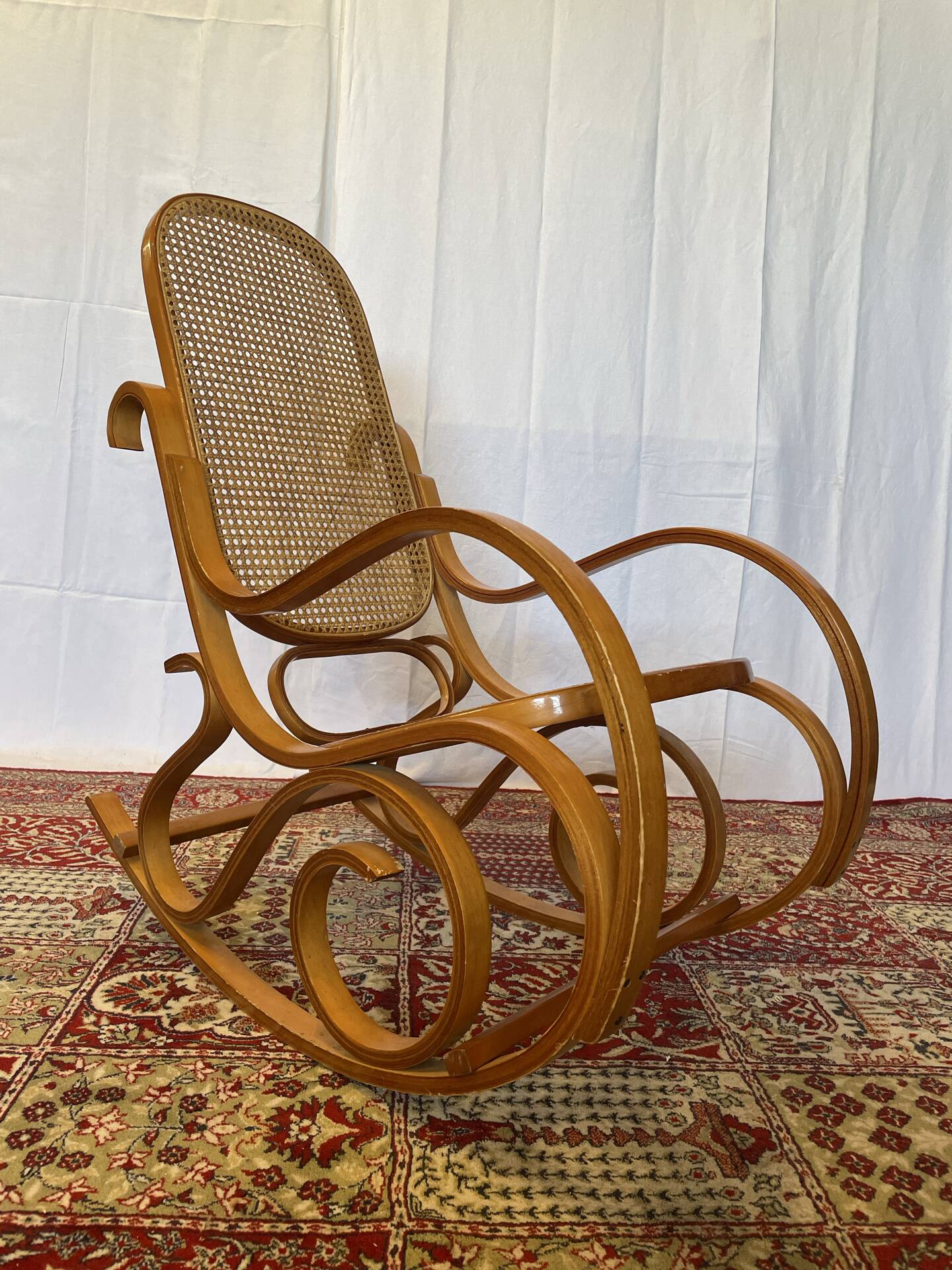 Antique rocking chair in curved wood and caning.