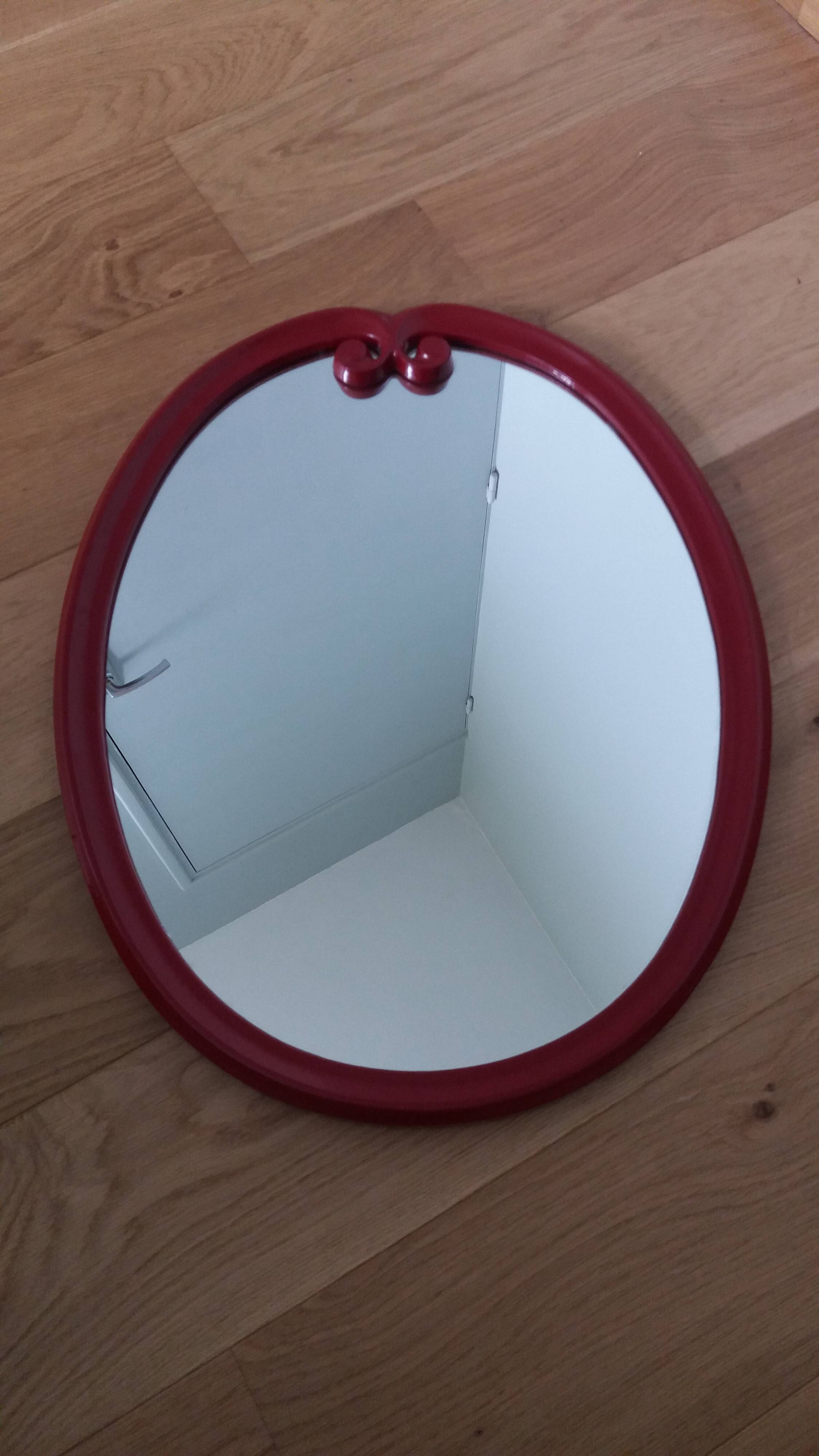 Oval mirror, red enamelled metal in Art Deco style, 49 x 39 cm.