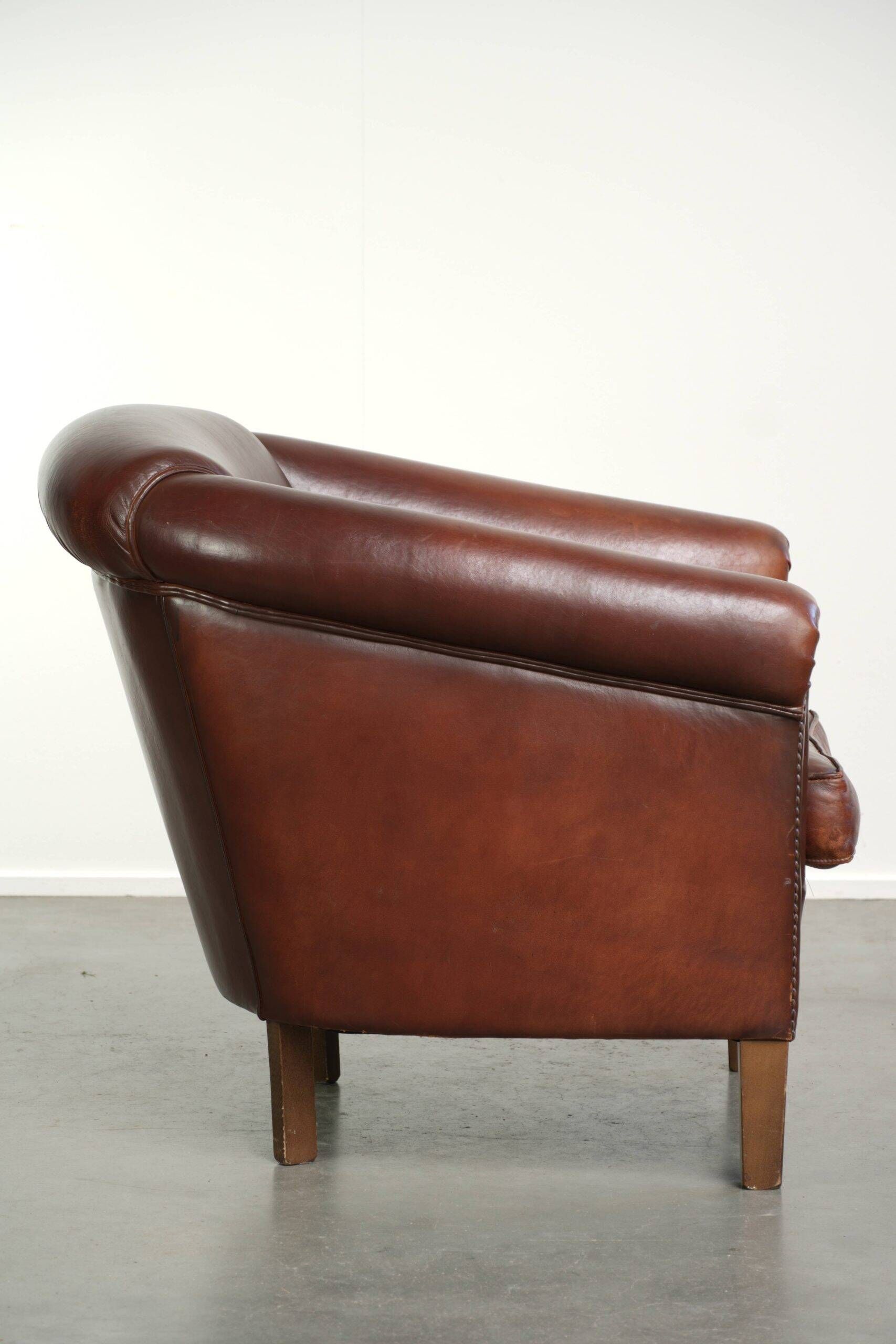 Characterful sheepskin club armchair in a dark cognac colour in English style