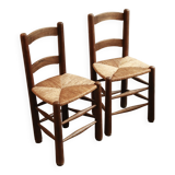 Pair of wooden chairs with woven straw seats.