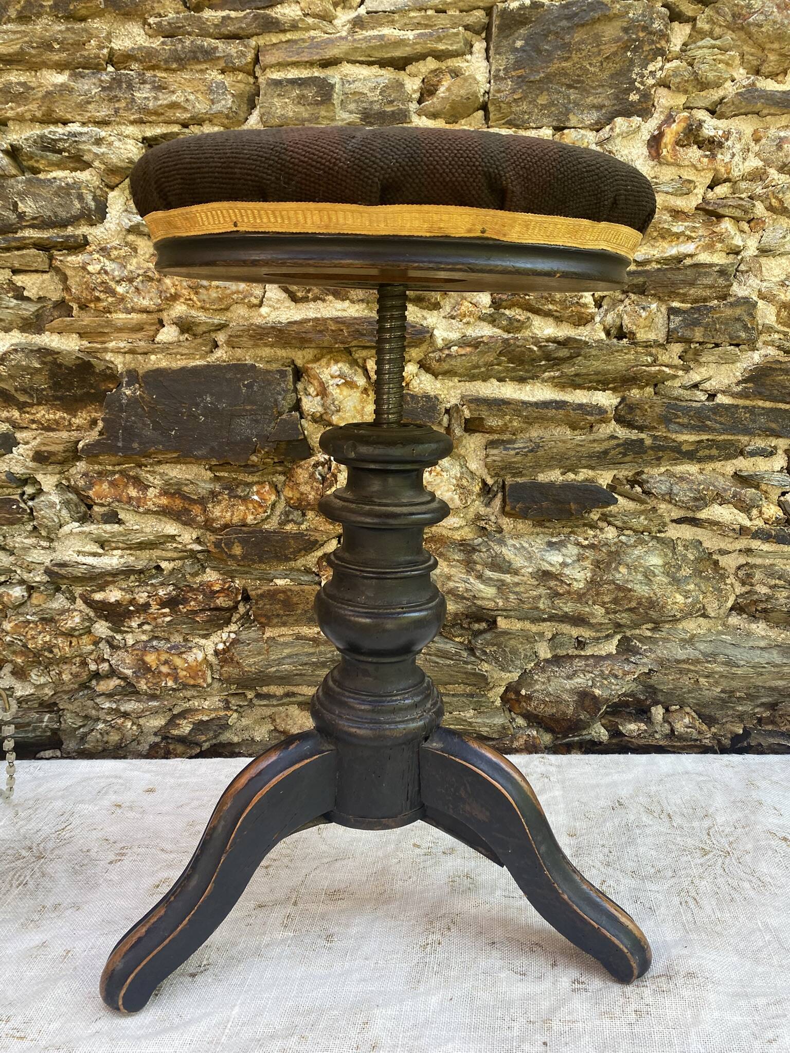 Old adjustable piano stool, blackened wood, metal screws, embroidered seat.