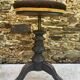 Old adjustable piano stool, blackened wood, metal screws, embroidered seat.