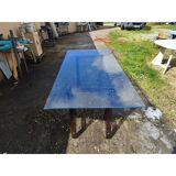 Vintage table with a glass top and smoked plastic trestle legs.