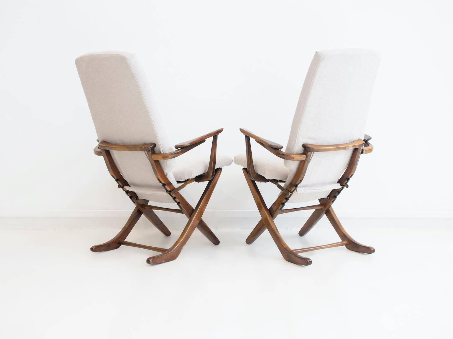 Pair of varnished wooden reclining armchairs, upholstered in lightweight fabric.