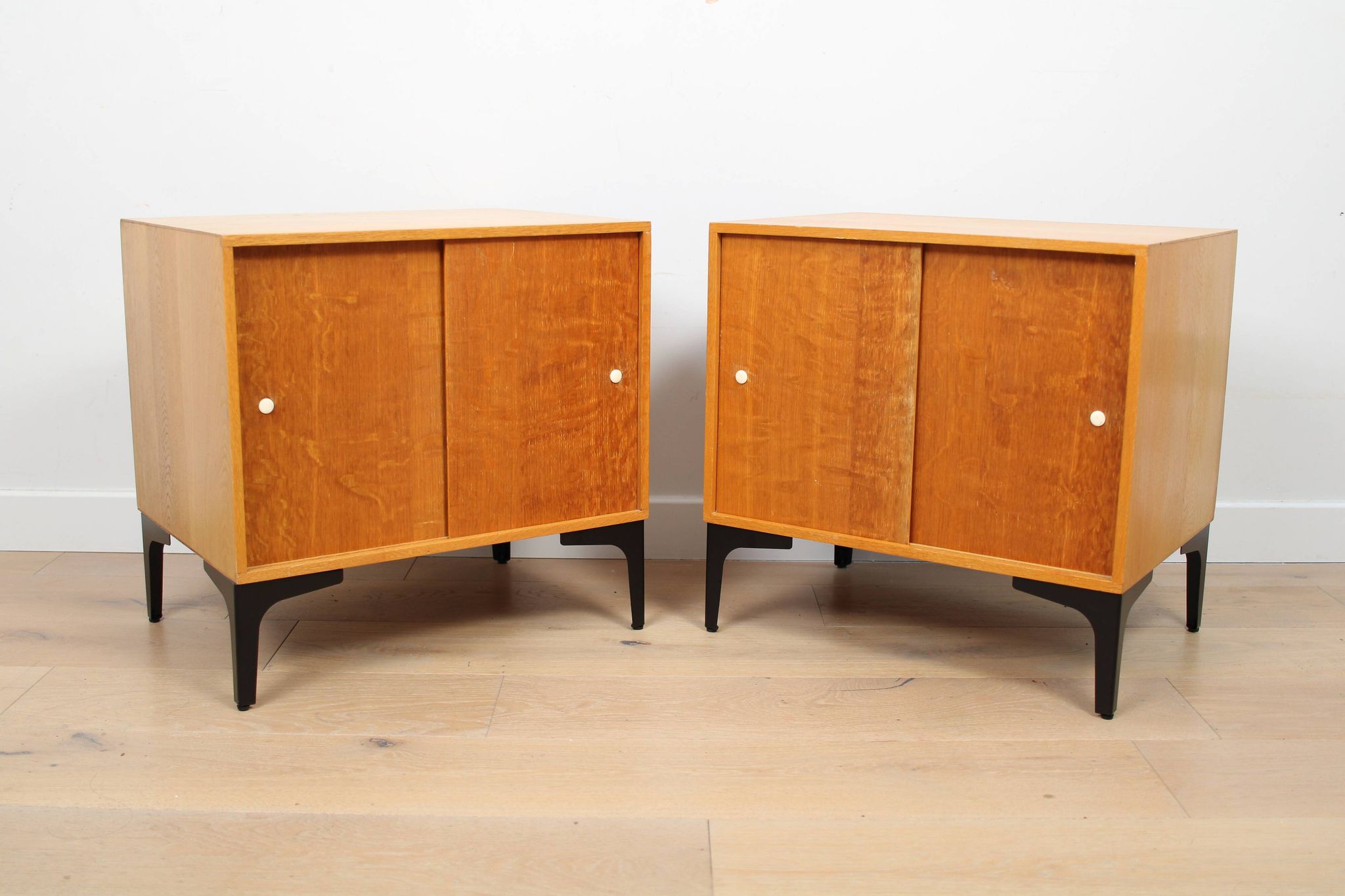A pair of vintage mid-century bedside tables with oak sliding doors