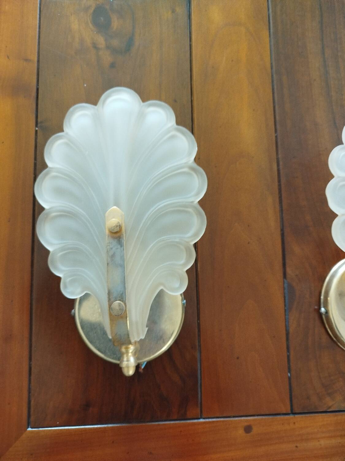 Pair of wall lights with frosted glass and brass shell design.