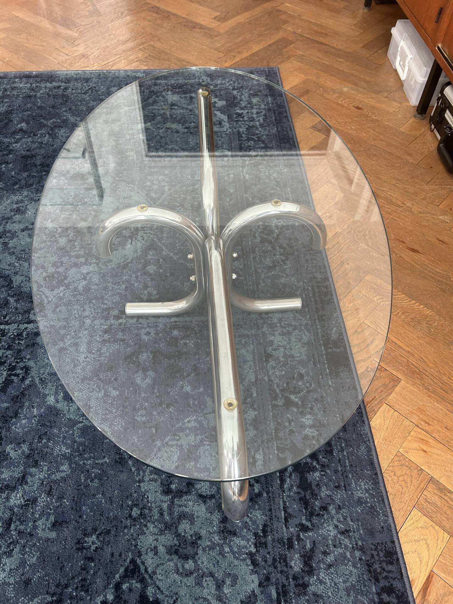 Oval glass coffee table with chrome legs, vintage 70s design.