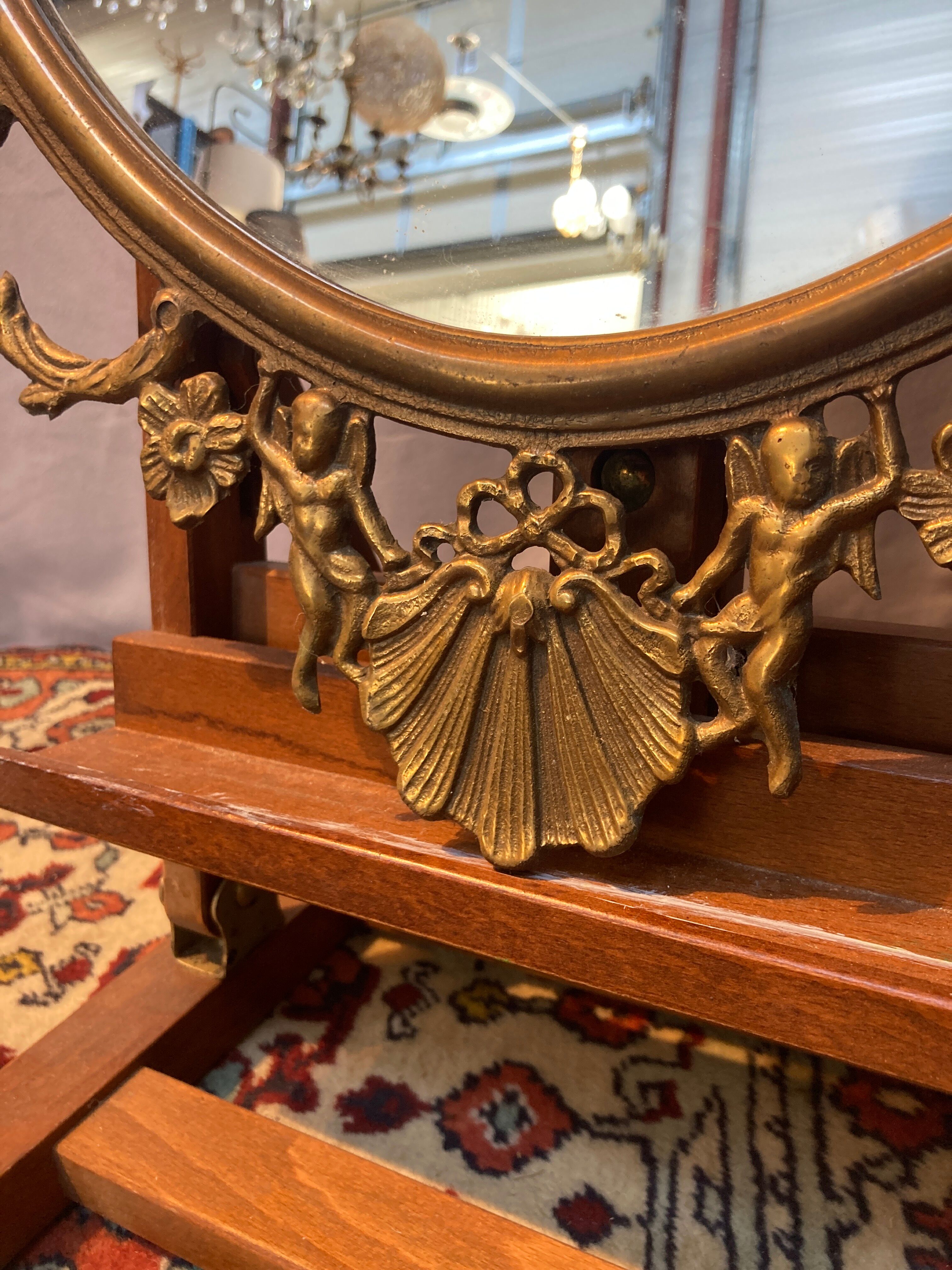Oval mirror in gilded brass, figures of cherubs and moldings