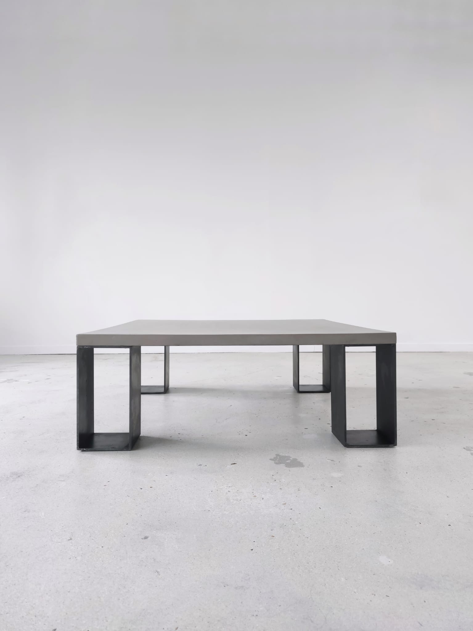 Table basse minimaliste en béton ciré et acier massif 1m20x1m20
