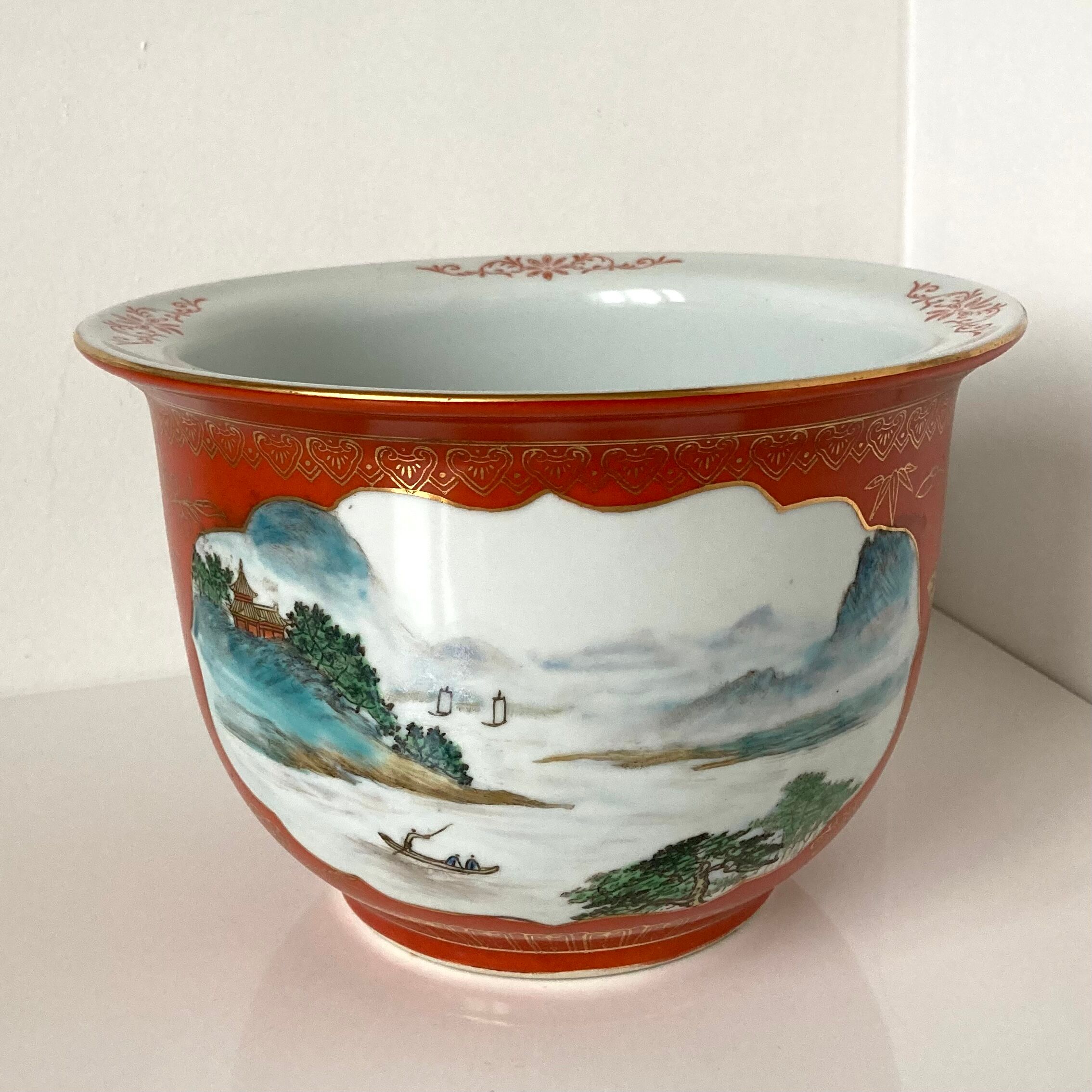 Chinese planter or Chinese porcelain pot cover decorated with landscapes on a coral and golden background