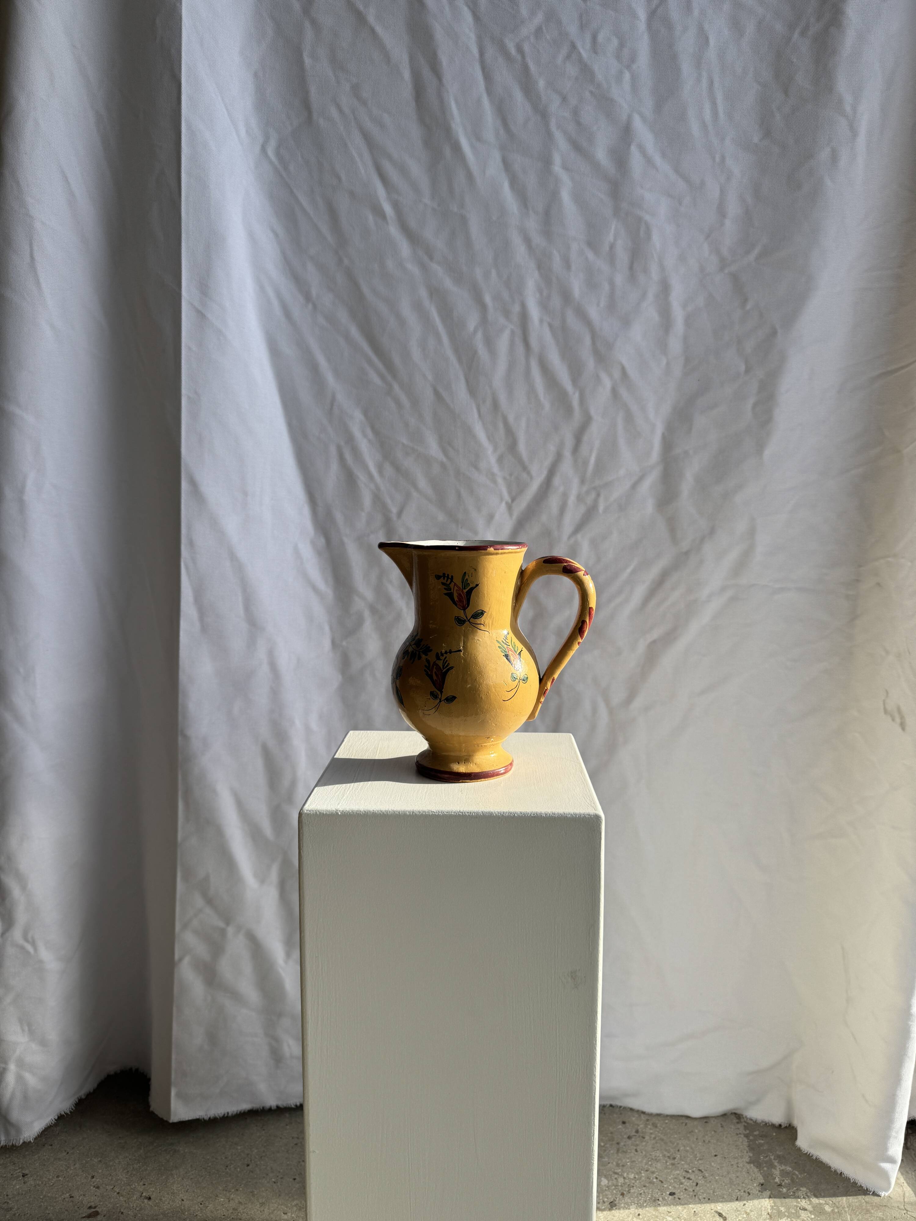 Large antique handmade ochre yellow jug with a pink flower pattern.