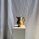 Large antique handmade ochre yellow jug with a pink flower pattern.