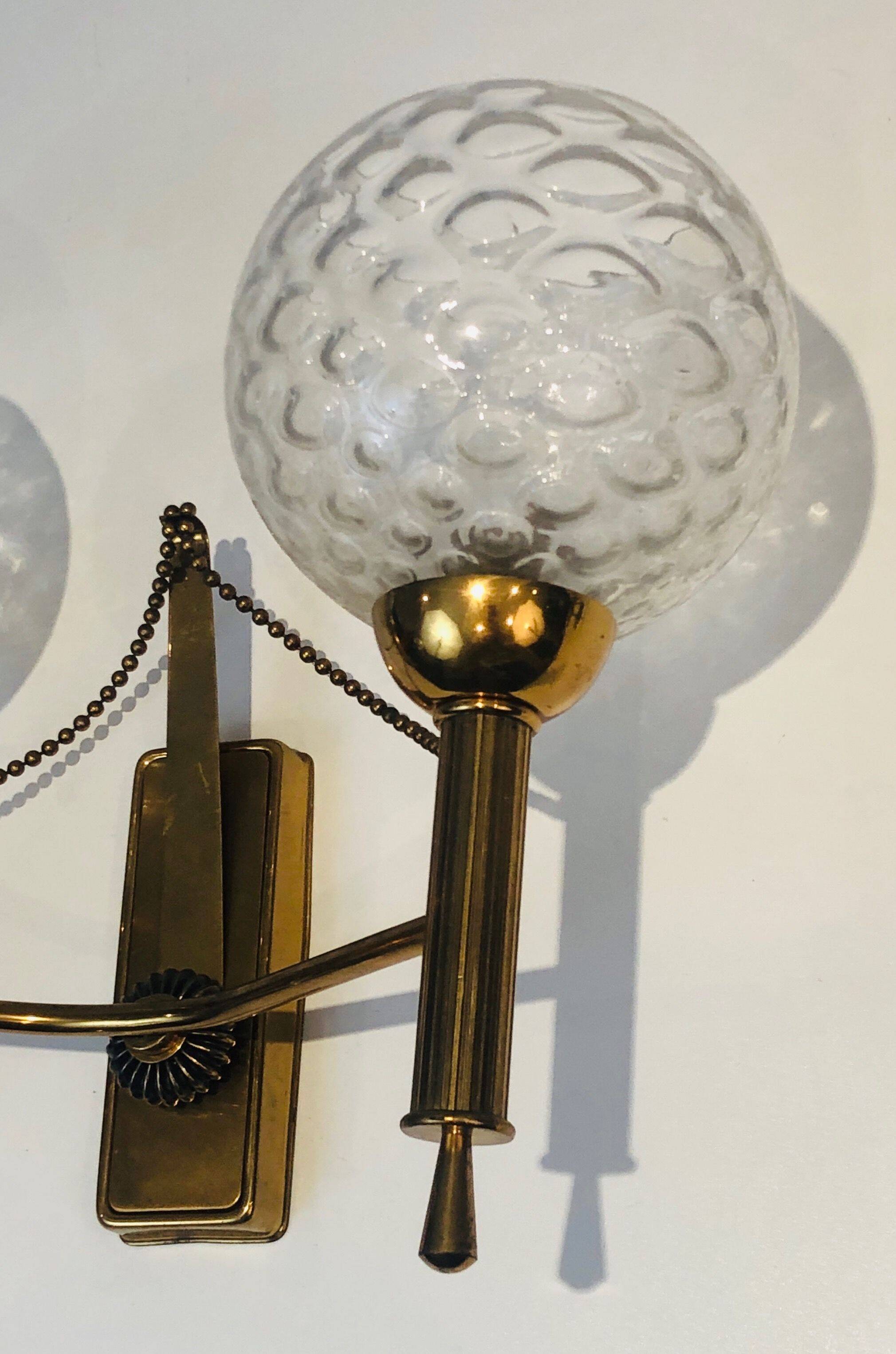 Pair of brass wall lights with glass globes. Around 1970.