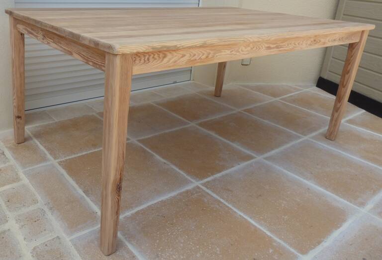 Large natural wood table with rectangular top supported by legs