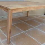 Large natural wood table with rectangular top supported by legs