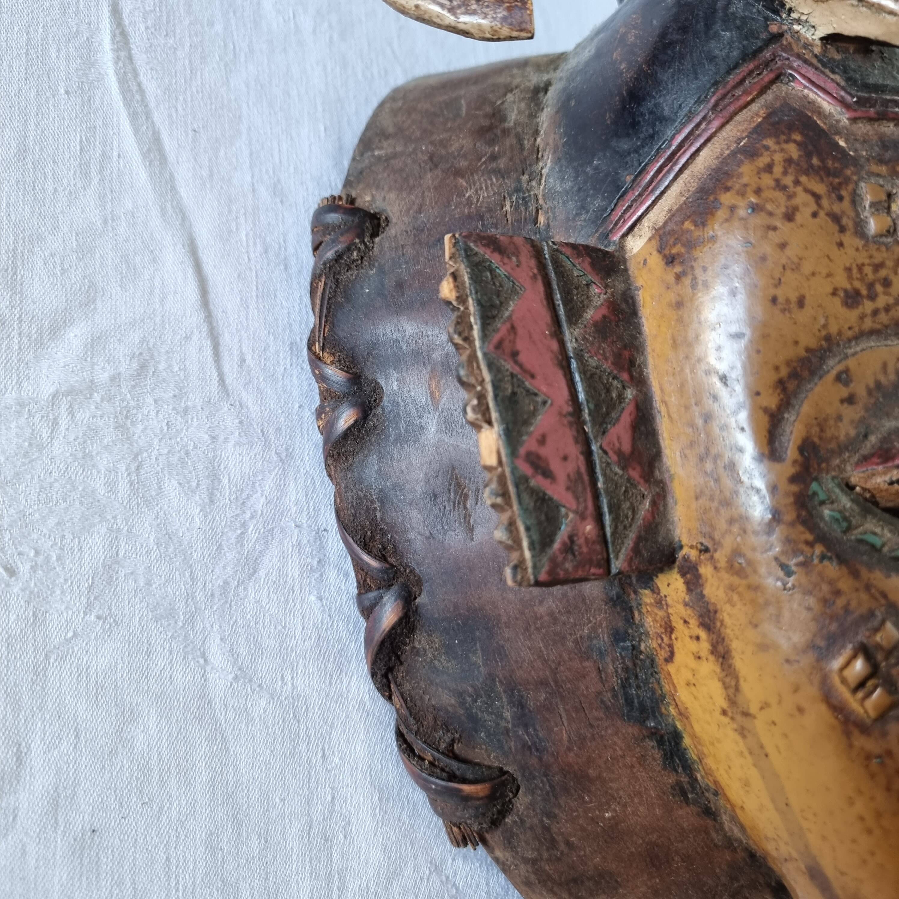 A large Senufo mask made of colored wood, decorated with an anthropomorphic figure