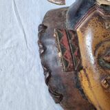 A large Senufo mask made of colored wood, decorated with an anthropomorphic figure