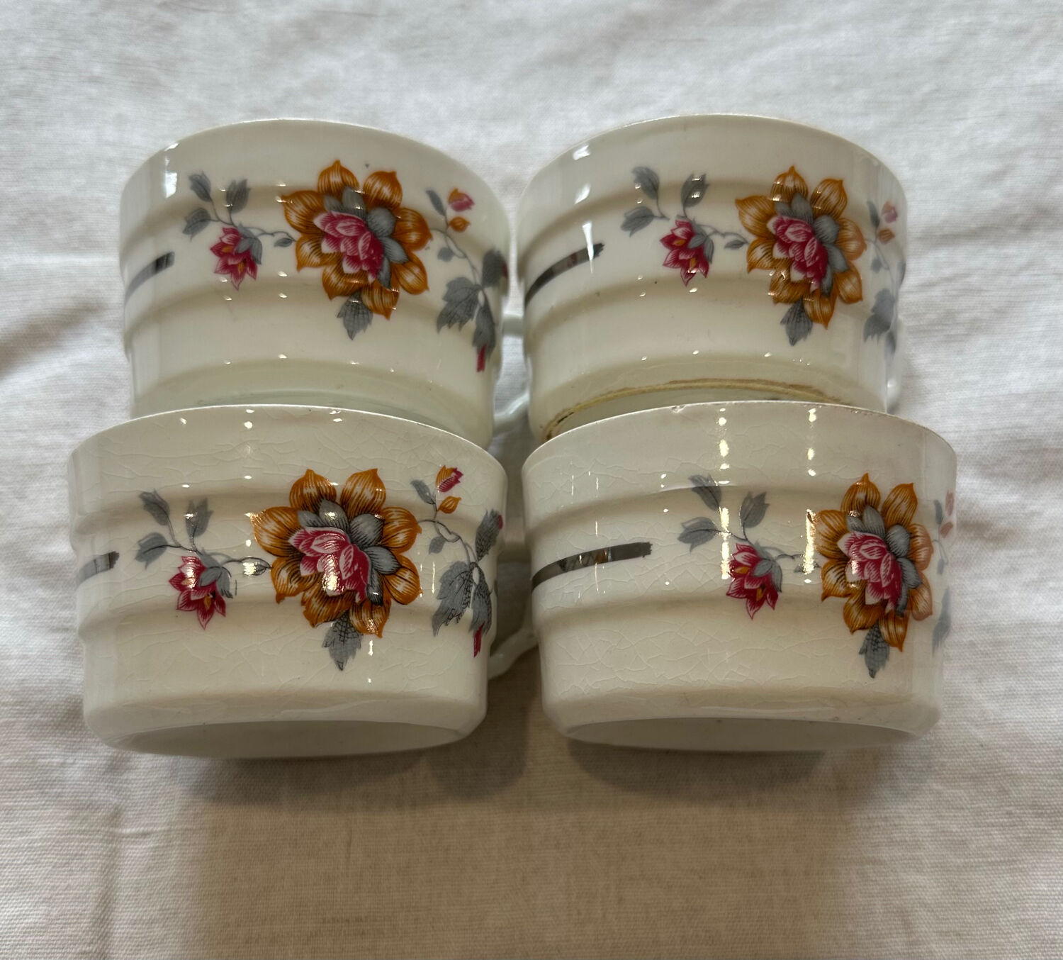 Set of 4 fine porcelain coffee cups with floral patterns and silver accents.