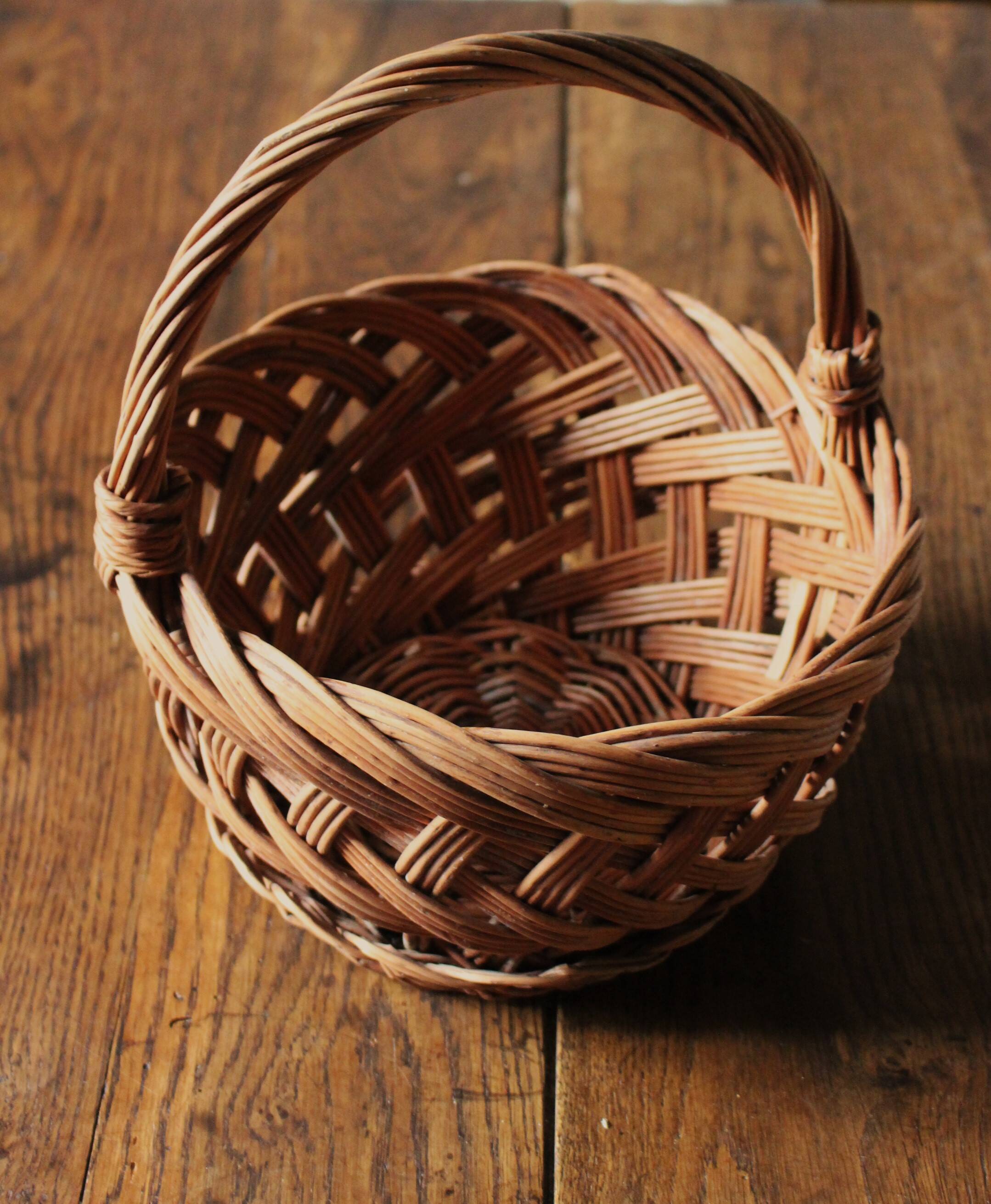 Round woven dark wicker basket with openwork vintage handle