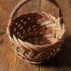 Round woven dark wicker basket with openwork vintage handle