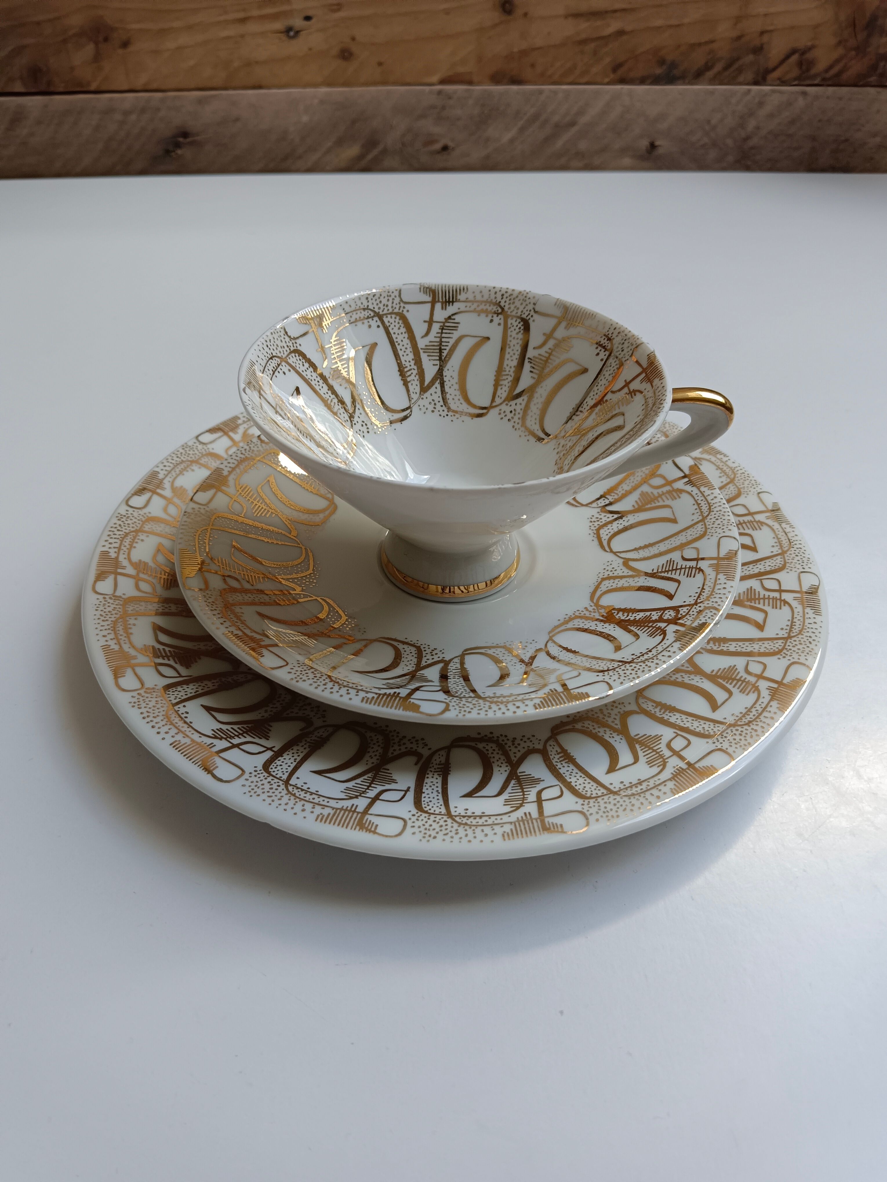 Solitaire tea cup, saucer, and dessert plate in white and gold.