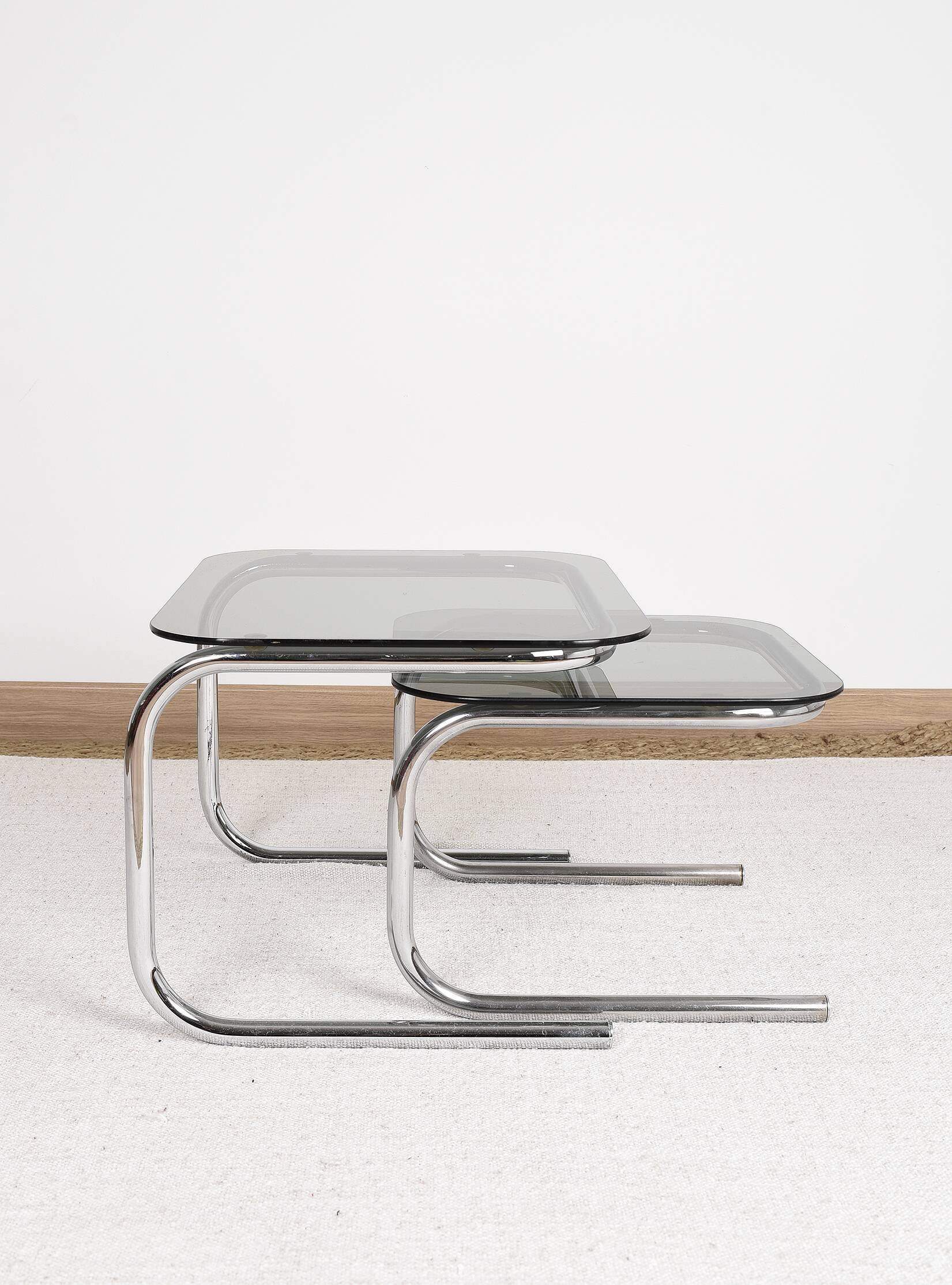 Pair of nesting tables in smoked glass and chrome legs.