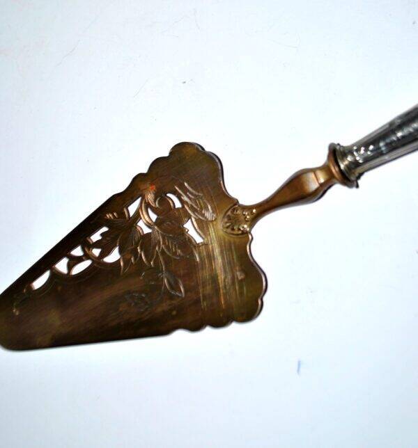 Antique silver-plated pie server with a brass blade decorated with roses.