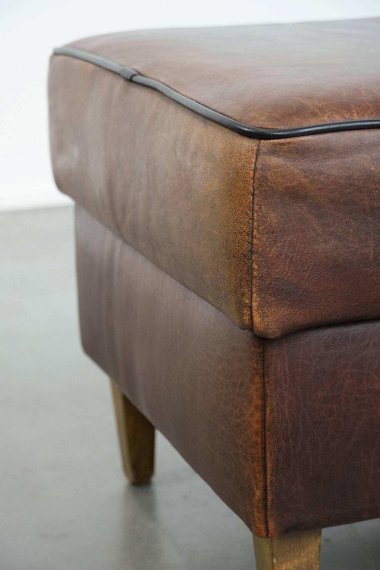 Sturdy vintage sheepskin ottoman in a beautiful large size with black piping