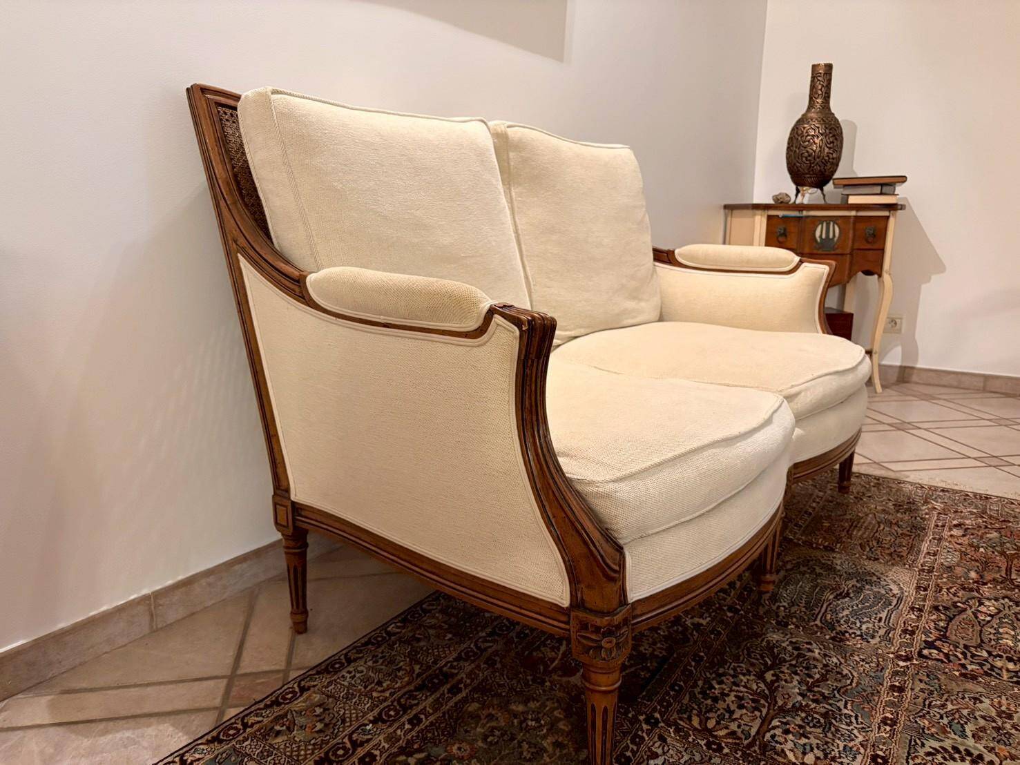 Two-seater canapé by Roche Bobois in Louis XVI style — carved wood, caned sides.