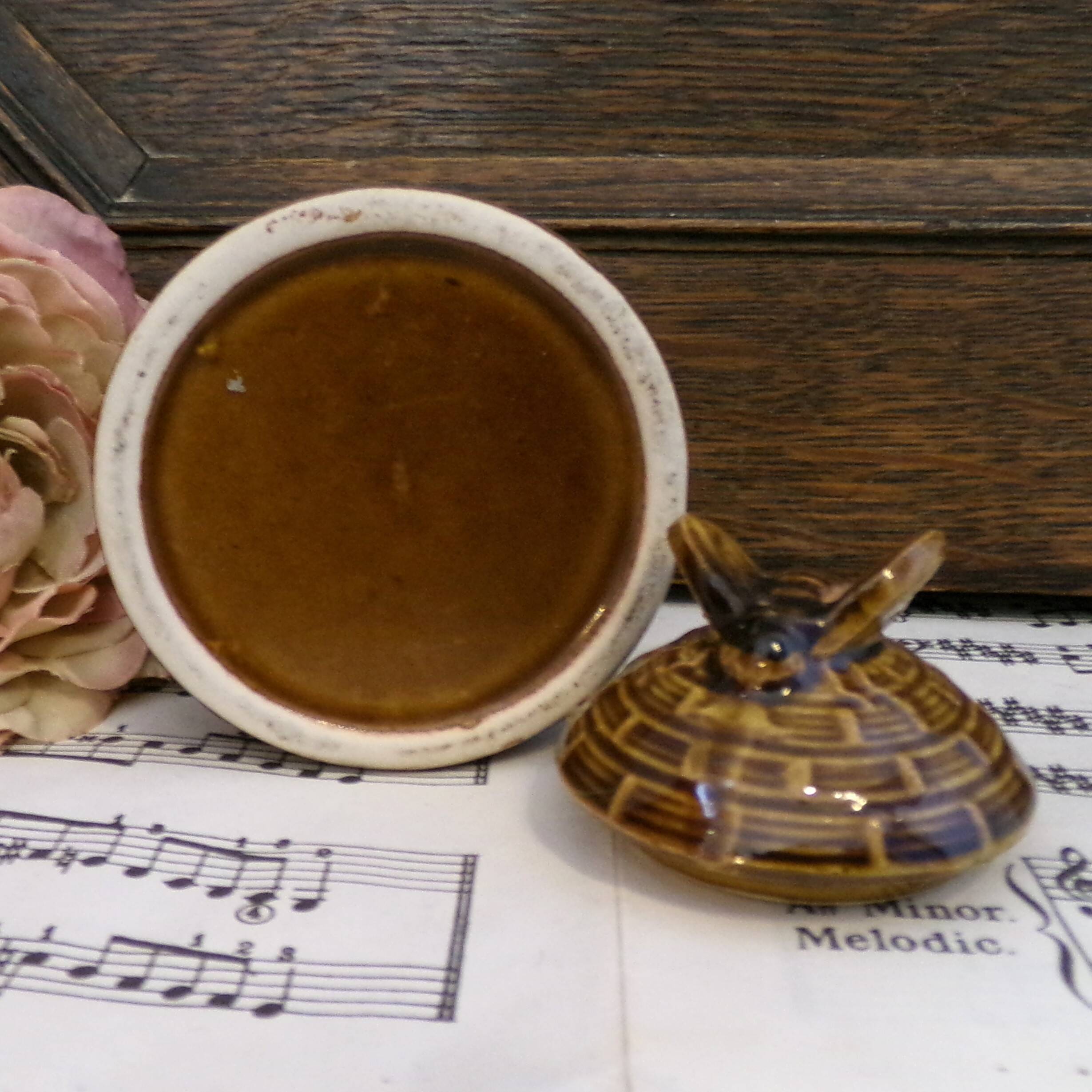 Honey pot in the shape of a hive decorated with bees.