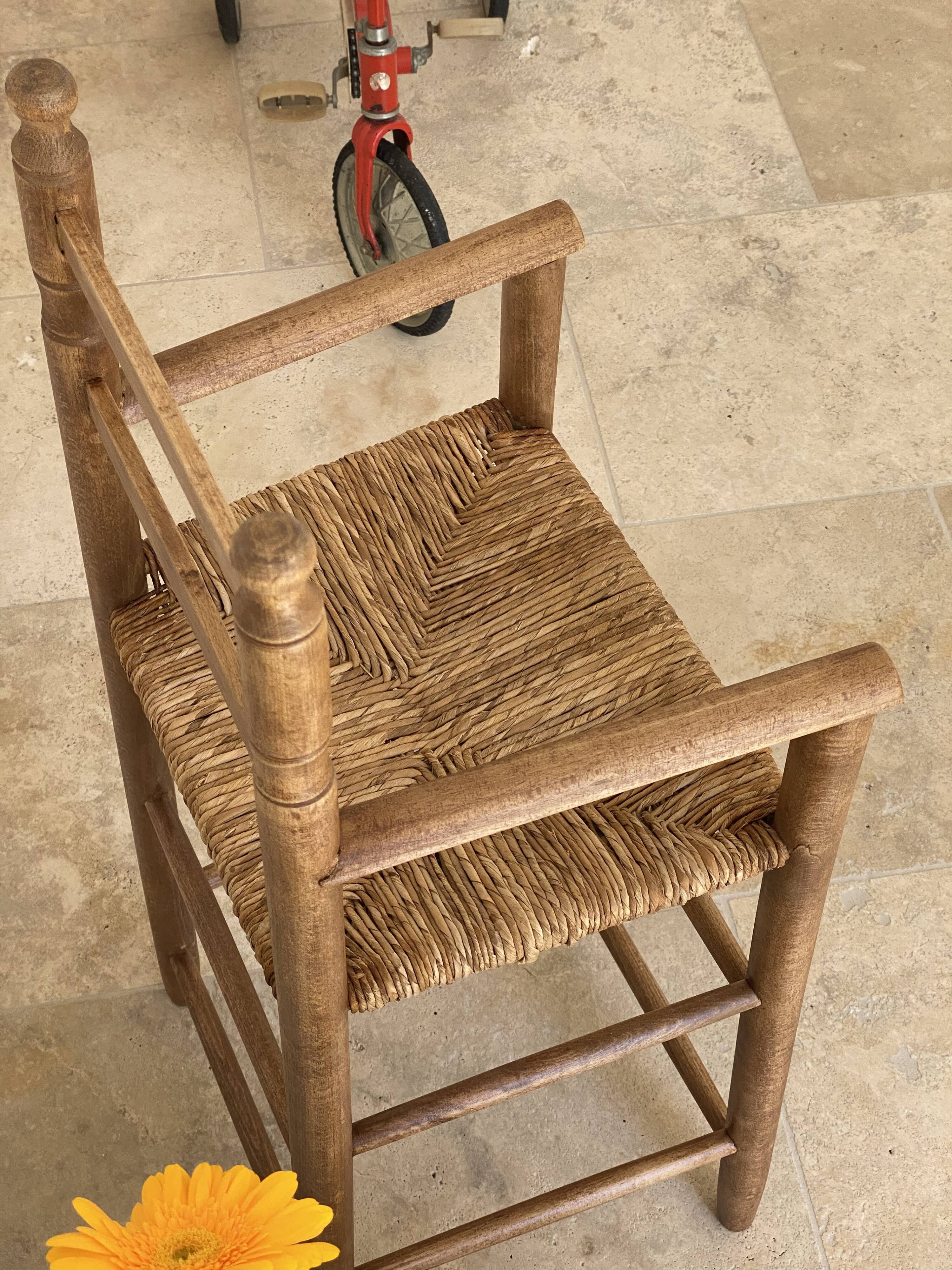 Old wooden high chair for children with a straw seat.