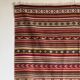 Large Indian rug with red, yellow, and white stripes and geometric fringes.