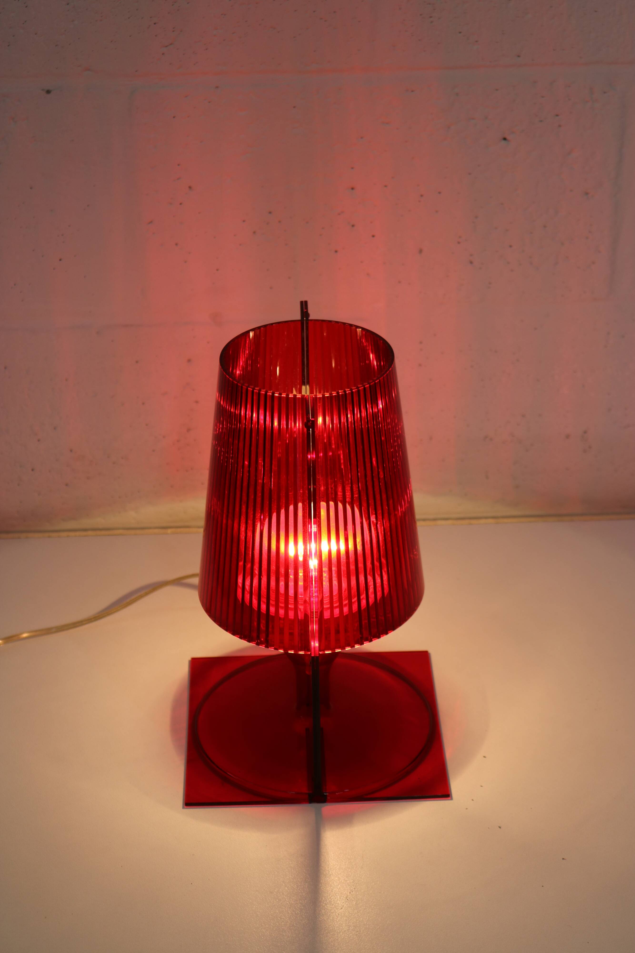 Red plastic Kartell table lamp - model Take - design by Ferruccio Laviani