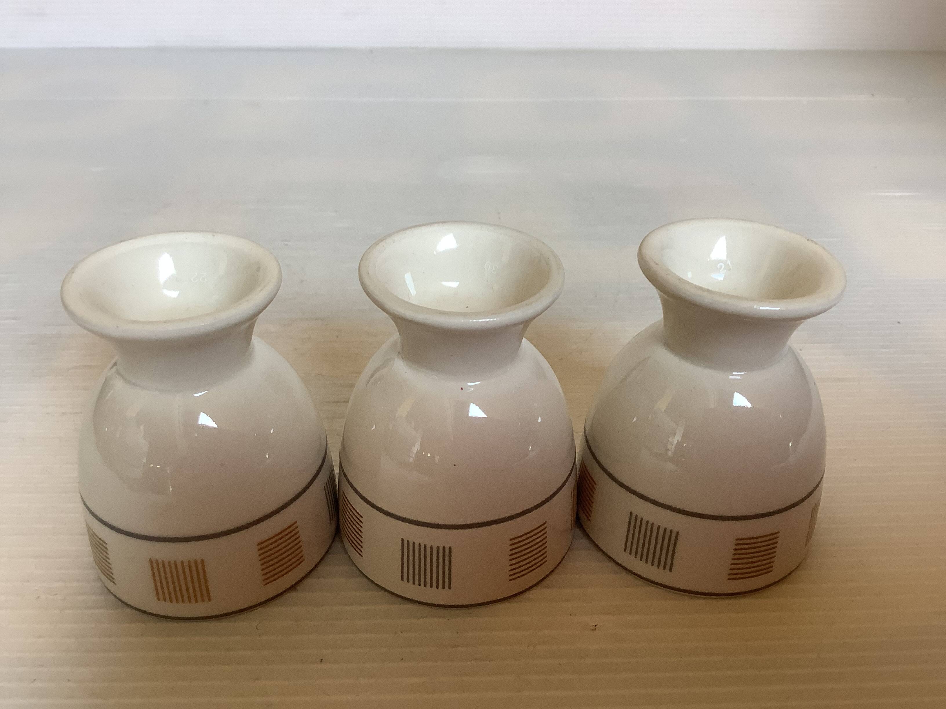 Three egg cups with geometric patterns in beige and brown.