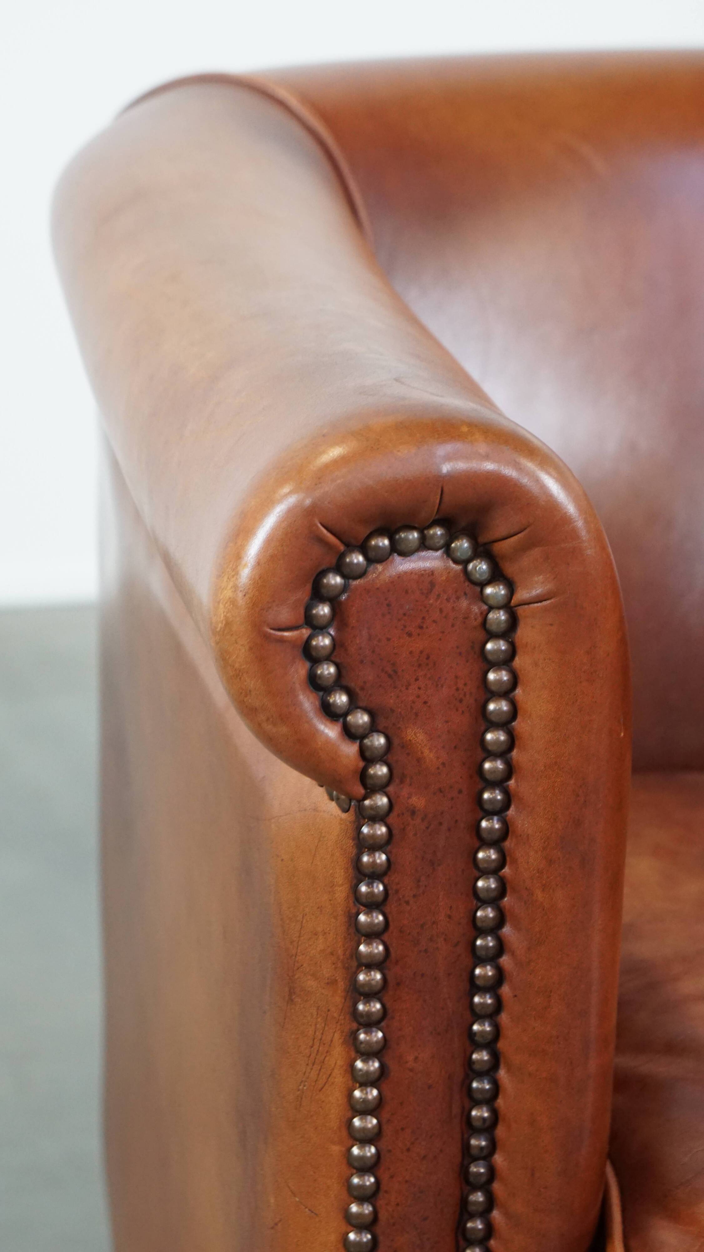 Cognac-colored cow leather club chair finished with decorative nails in English style