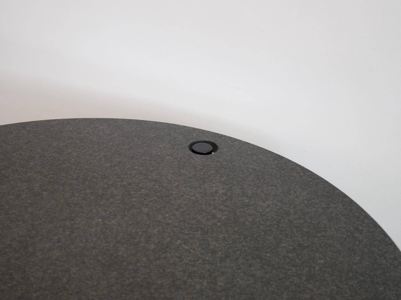 Round dining table in black lacquered metal with a granite top.