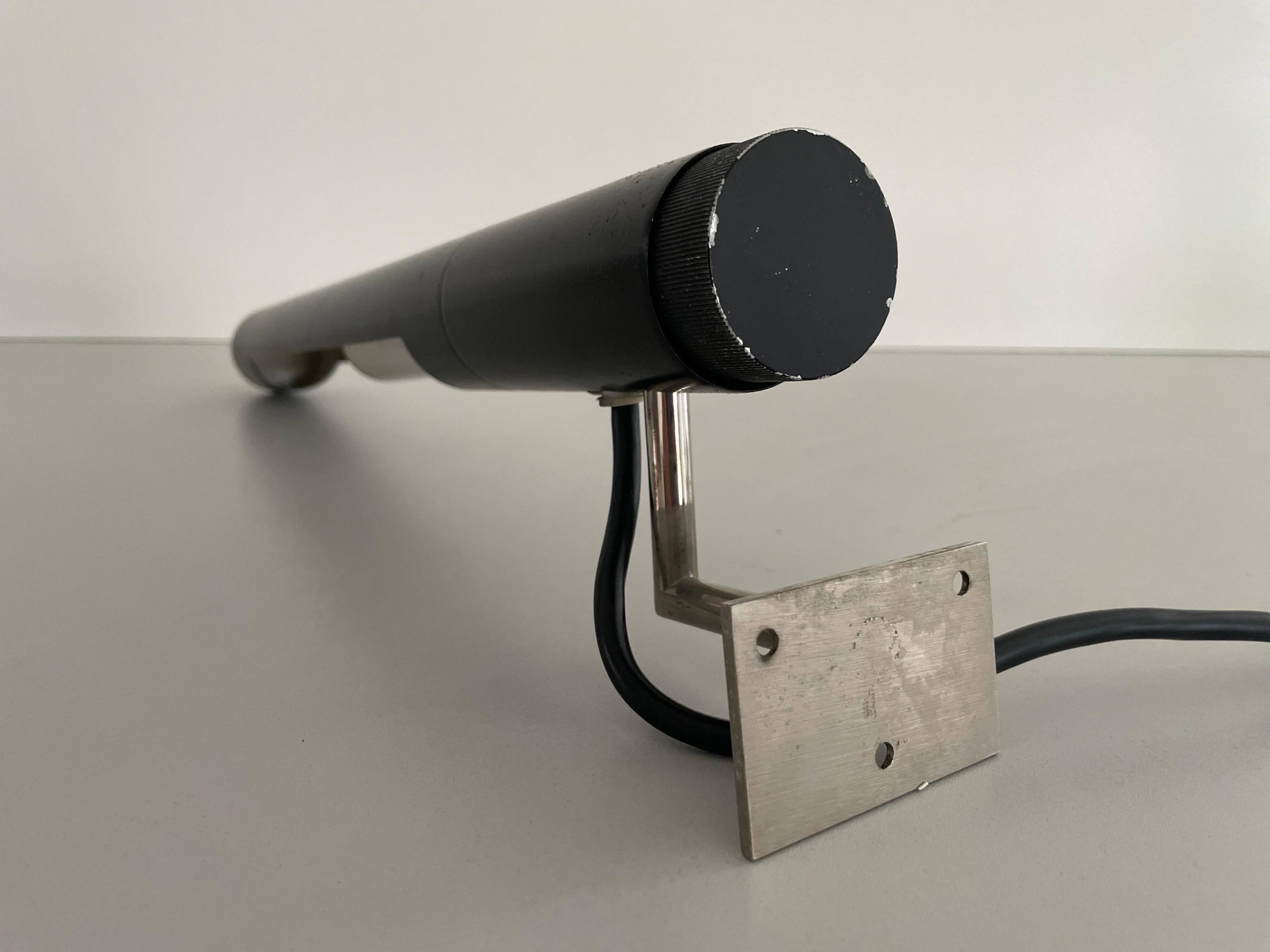 Minimalist black metal wall light with a cylindrical design, 1960s, Germany.