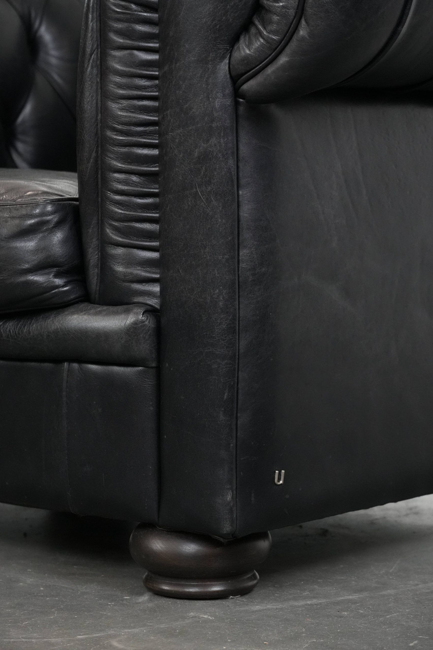 Comfortable black chesterfield armchair made of cowhide leather