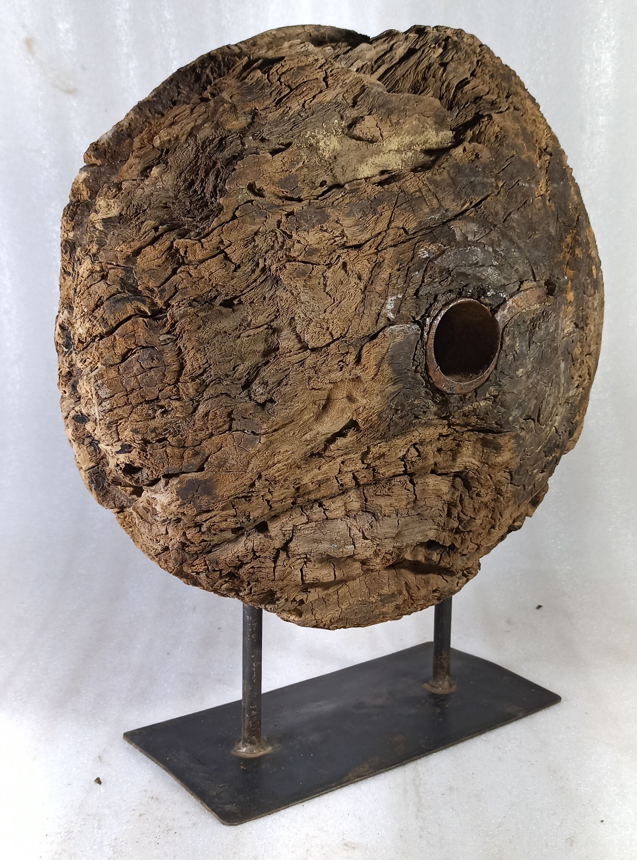 Old wooden pulley wheel on foot