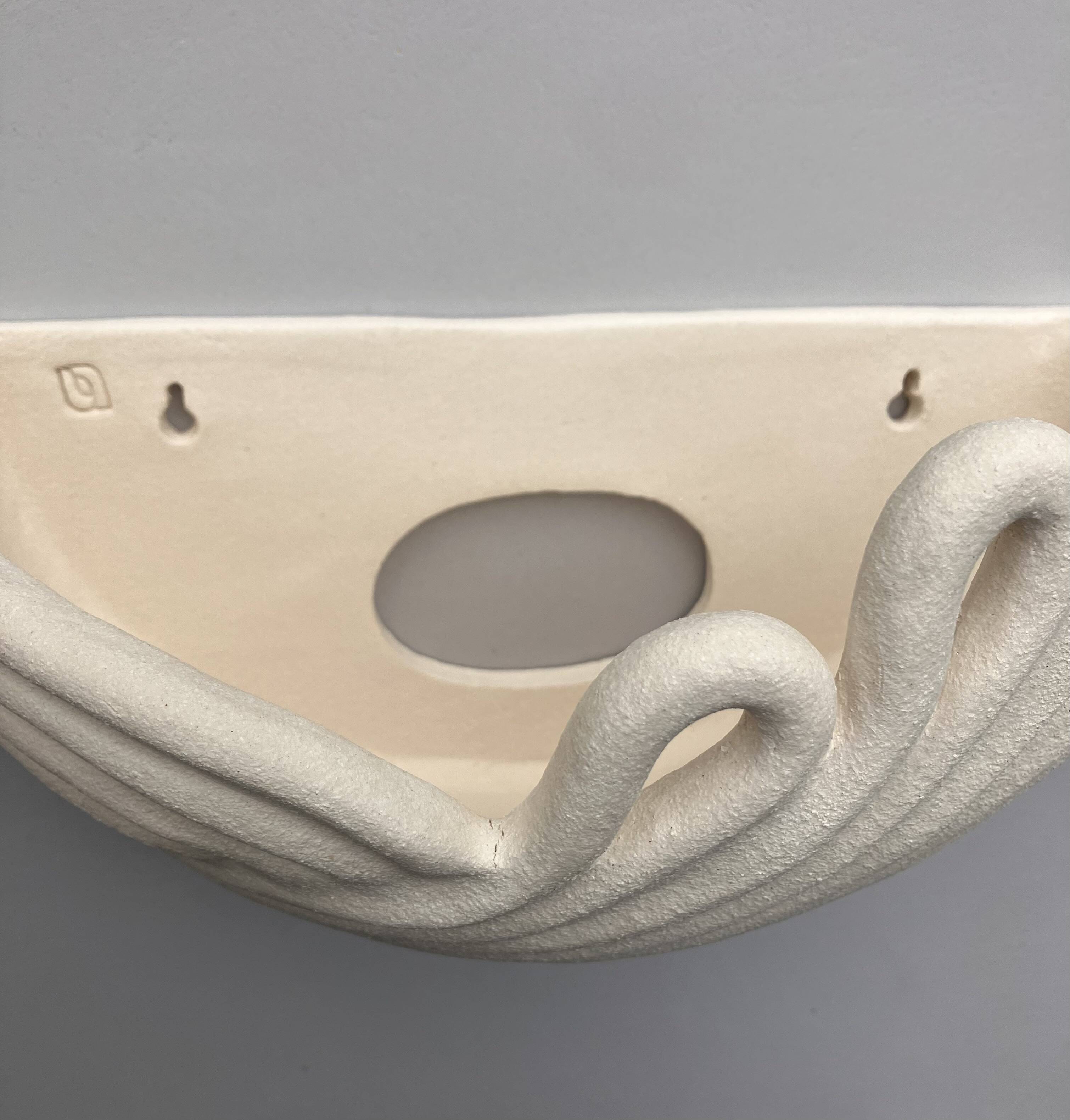 Draped ceramic wall light in a half-moon shape.